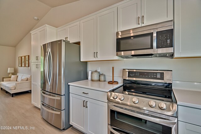 kitchen featuring white cabinets, vaulted ceiling, light hardwood / wood-style flooring, and stainless steel appliances