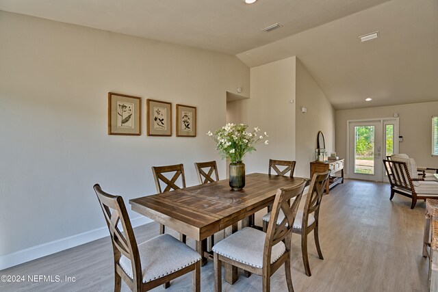 dining space with vaulted ceiling, french doors, and light wood-type flooring