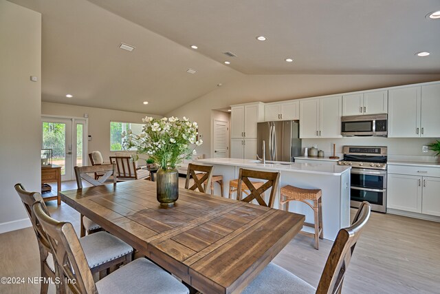 dining room featuring vaulted ceiling and light hardwood / wood-style flooring