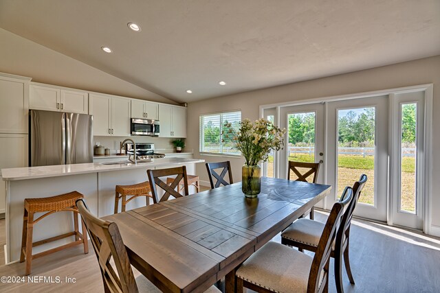 dining area with light hardwood / wood-style floors, sink, and lofted ceiling