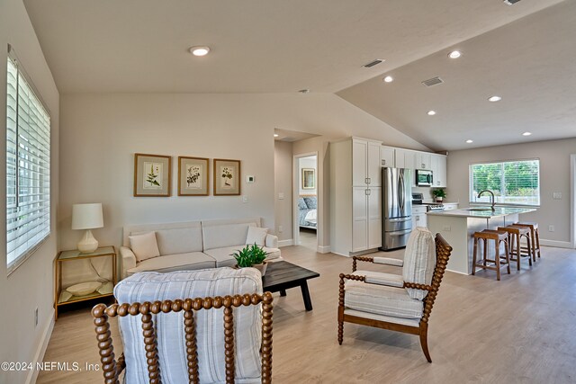 bedroom with light hardwood / wood-style flooring, lofted ceiling, and stainless steel fridge