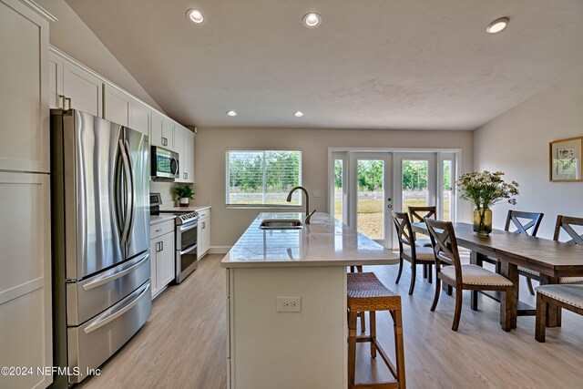 kitchen with appliances with stainless steel finishes, light hardwood / wood-style floors, an island with sink, white cabinetry, and sink