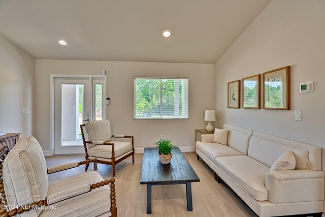 living room with plenty of natural light, light hardwood / wood-style floors, and lofted ceiling