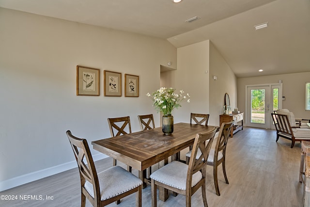 dining space with french doors, vaulted ceiling, and light wood-type flooring