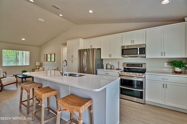 kitchen featuring stainless steel appliances, lofted ceiling, white cabinetry, sink, and light wood-type flooring