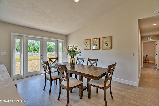 dining room with lofted ceiling, a healthy amount of sunlight, french doors, and light wood-type flooring