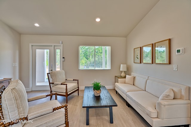 living room featuring lofted ceiling, plenty of natural light, and light wood-type flooring