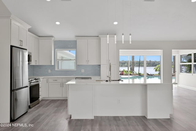 kitchen with a healthy amount of sunlight, sink, stainless steel appliances, and an island with sink