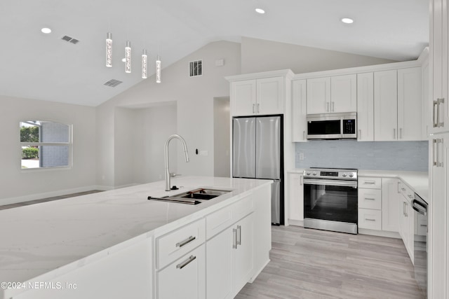 kitchen featuring white cabinetry, stainless steel appliances, vaulted ceiling, light hardwood / wood-style flooring, and light stone countertops