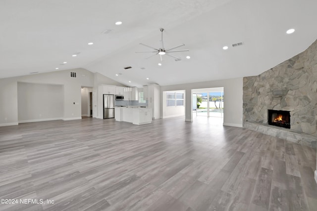 unfurnished living room featuring high vaulted ceiling, light hardwood / wood-style flooring, ceiling fan, and a fireplace