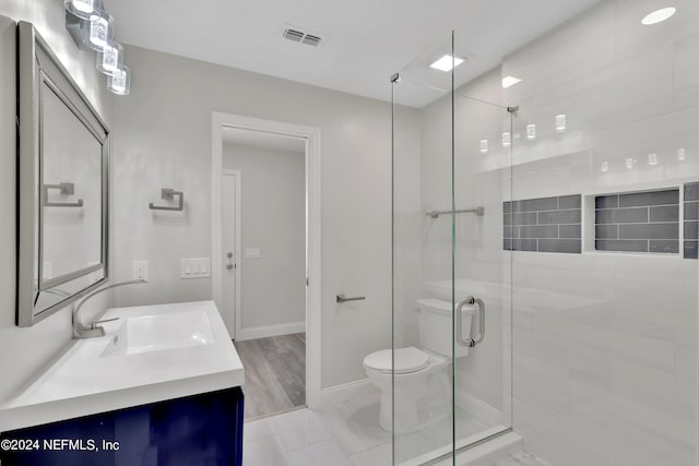 bathroom with a shower with door, vanity, toilet, and tile flooring