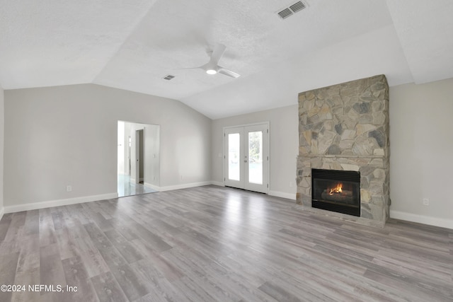 unfurnished living room featuring a stone fireplace, ceiling fan, hardwood / wood-style floors, and lofted ceiling