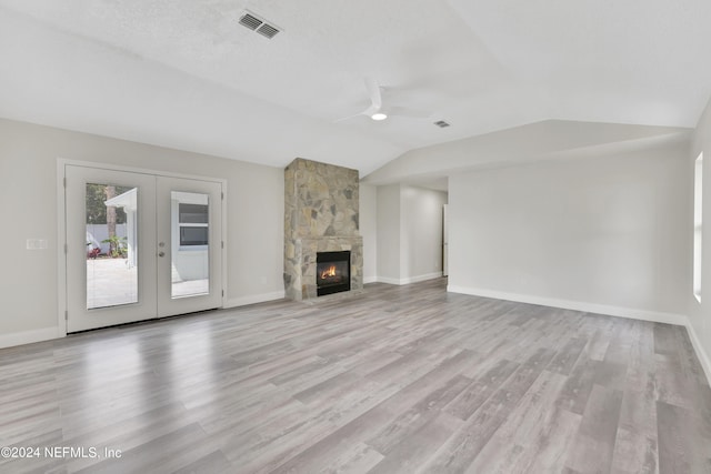 unfurnished living room featuring a stone fireplace, light wood-type flooring, and lofted ceiling