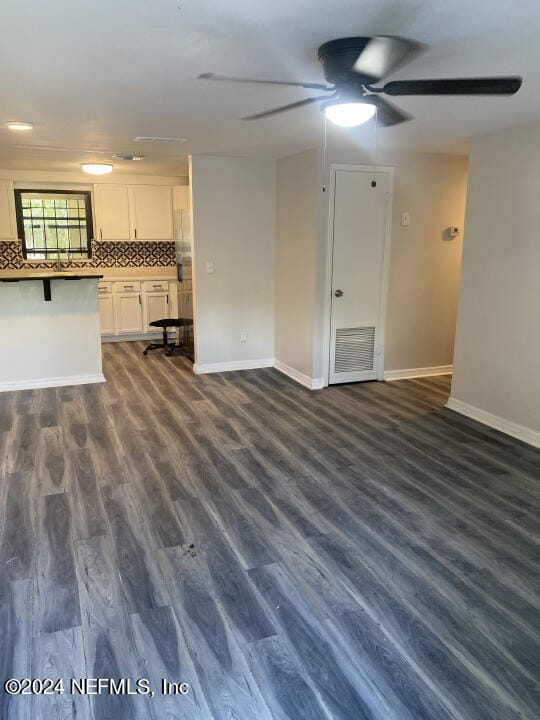 unfurnished living room featuring dark hardwood / wood-style floors and ceiling fan