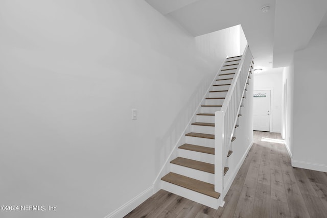 stairway with light hardwood / wood-style floors