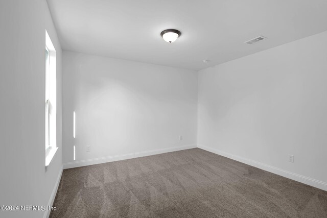 spare room featuring dark colored carpet