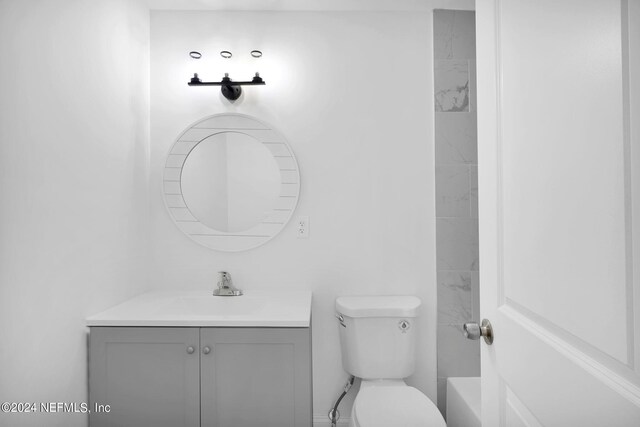 full bathroom featuring tiled shower / bath, vanity, and toilet