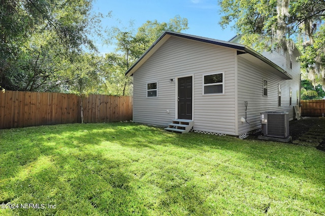 rear view of property with central AC and a lawn