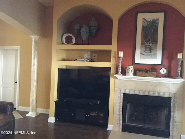 living room with built in features, a tile fireplace, and ornate columns