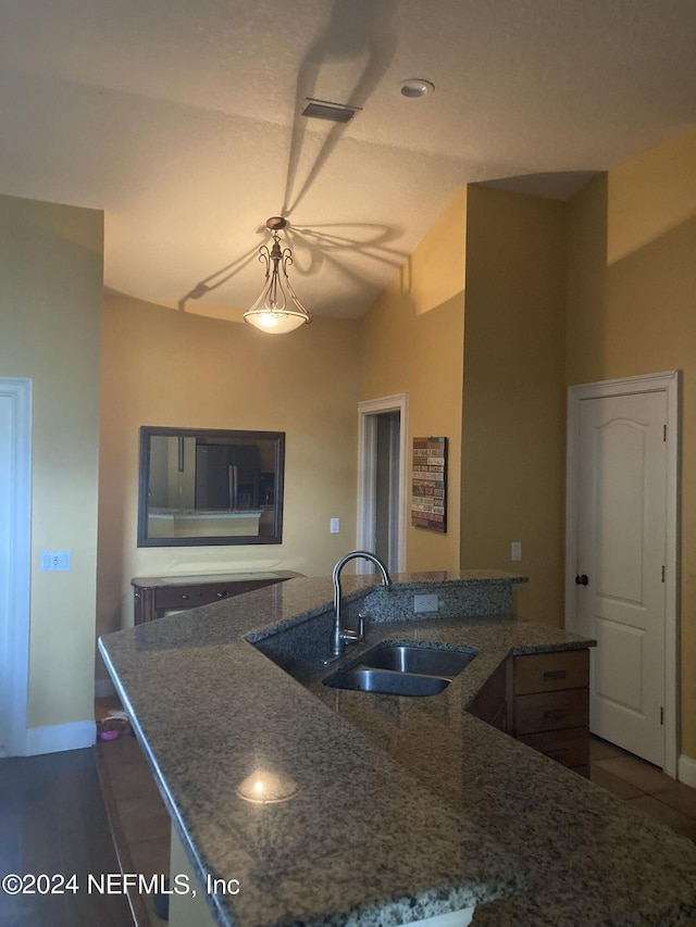 kitchen with sink, a kitchen island with sink, and dark stone counters