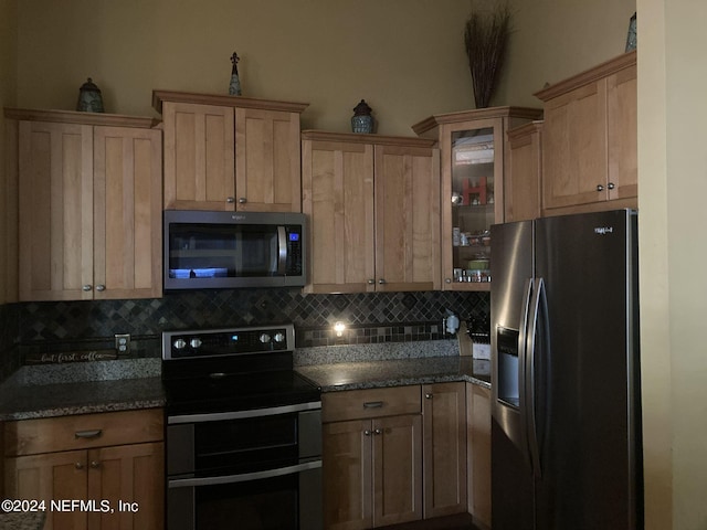 kitchen featuring tasteful backsplash, dark stone countertops, and stainless steel appliances