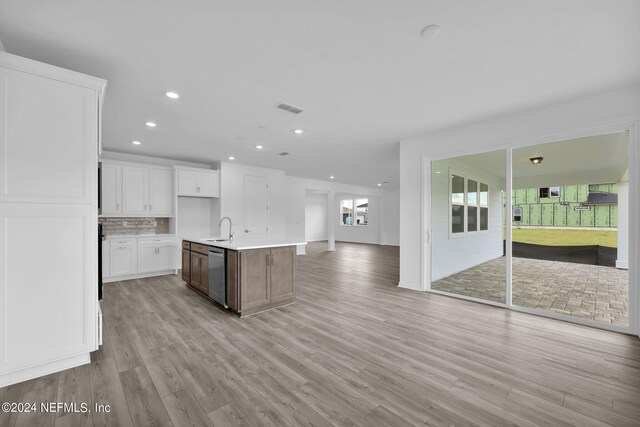 kitchen featuring light wood-type flooring, white cabinetry, a kitchen island with sink, and stainless steel dishwasher