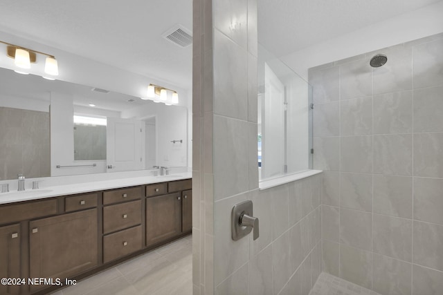 bathroom with tile patterned floors, tiled shower, and vanity