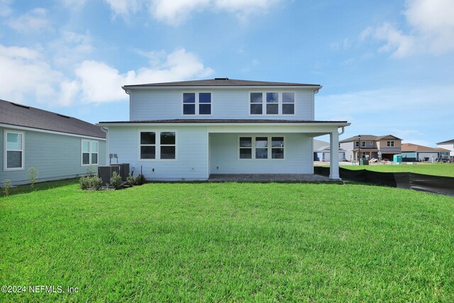 rear view of house featuring cooling unit and a yard