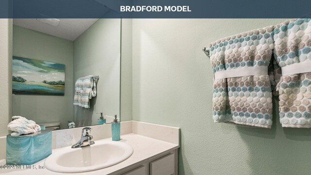 bathroom with a textured ceiling, vanity, and toilet