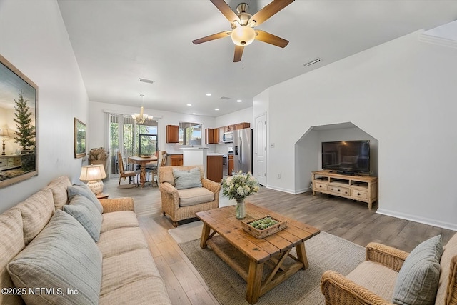 living room with hardwood / wood-style flooring and ceiling fan with notable chandelier