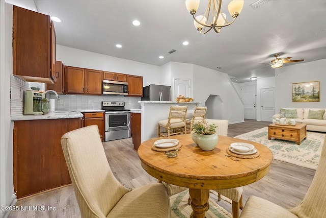 kitchen featuring sink, hanging light fixtures, light hardwood / wood-style flooring, appliances with stainless steel finishes, and decorative backsplash