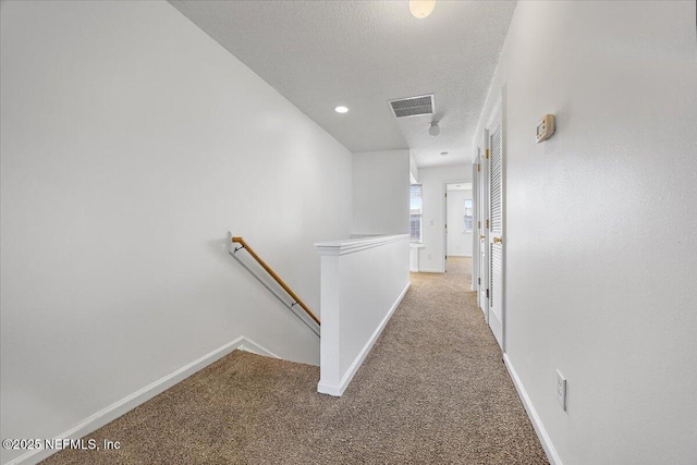 hall with light colored carpet and a textured ceiling