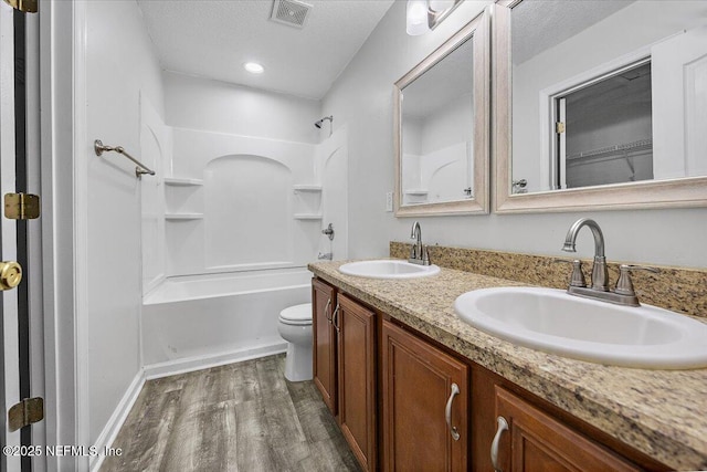 full bathroom with toilet, bathing tub / shower combination, wood-type flooring, a textured ceiling, and vanity