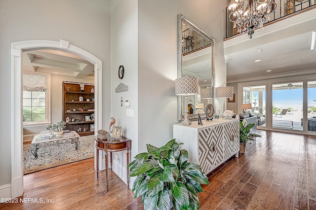 corridor with a healthy amount of sunlight, a notable chandelier, crown molding, and hardwood / wood-style floors