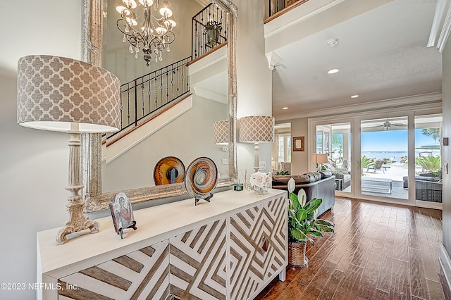 interior space featuring ornamental molding, an inviting chandelier, a towering ceiling, and hardwood / wood-style flooring