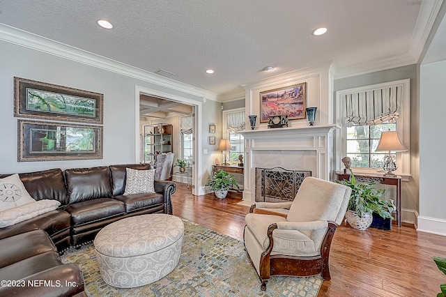 living room featuring hardwood / wood-style floors, a textured ceiling, crown molding, and a premium fireplace