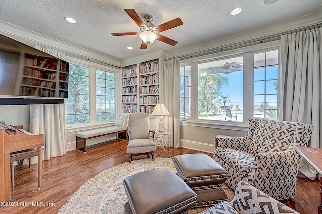 sitting room featuring hardwood / wood-style flooring, crown molding, ceiling fan, and a textured ceiling