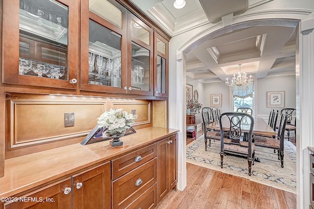 bar with coffered ceiling, light hardwood / wood-style floors, hanging light fixtures, a chandelier, and crown molding