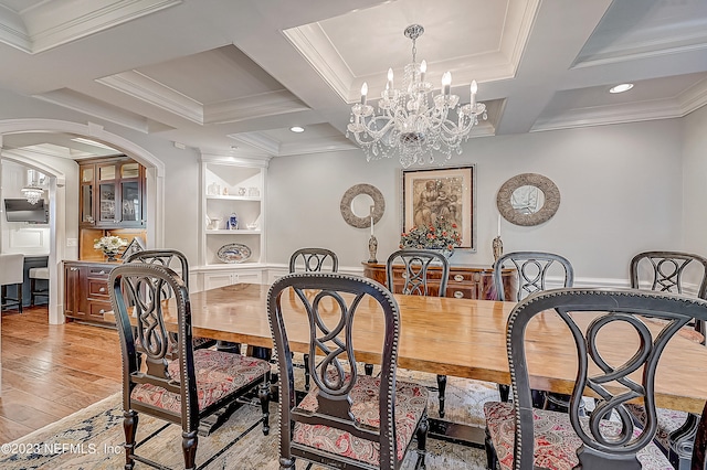 dining space featuring ornamental molding, coffered ceiling, light hardwood / wood-style floors, and a notable chandelier