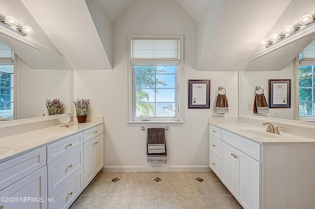 bathroom featuring oversized vanity, vaulted ceiling, and tile flooring