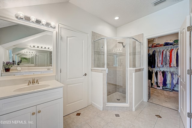 bathroom featuring walk in shower, a textured ceiling, vanity, and tile flooring