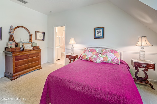 bedroom featuring ensuite bath, carpet floors, and vaulted ceiling