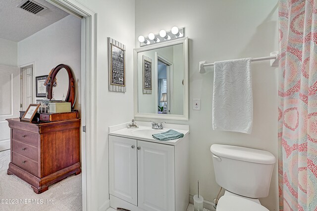 bathroom featuring a textured ceiling, vanity with extensive cabinet space, and toilet