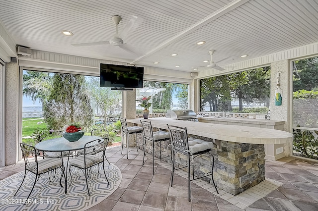 view of patio featuring exterior bar, ceiling fan, grilling area, and an outdoor kitchen