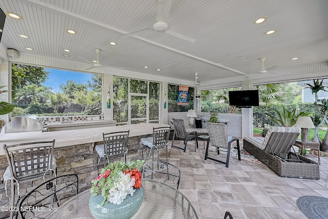 view of terrace featuring exterior kitchen, ceiling fan, area for grilling, and an outdoor bar