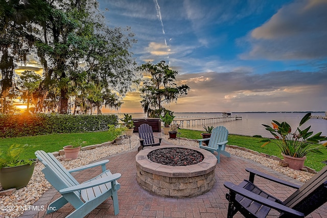 patio terrace at dusk with a water view and a fire pit