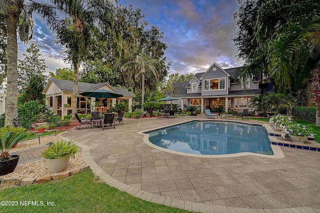 pool at dusk featuring a patio area