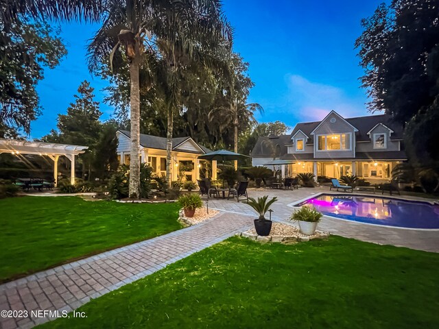 back house at dusk featuring a patio and a yard