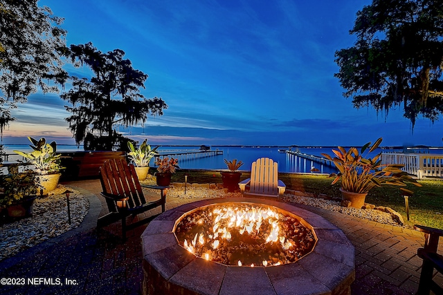 patio terrace at dusk with a water view and a fire pit