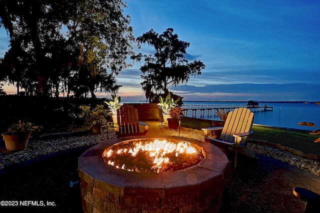 patio terrace at dusk featuring a water view and a fire pit